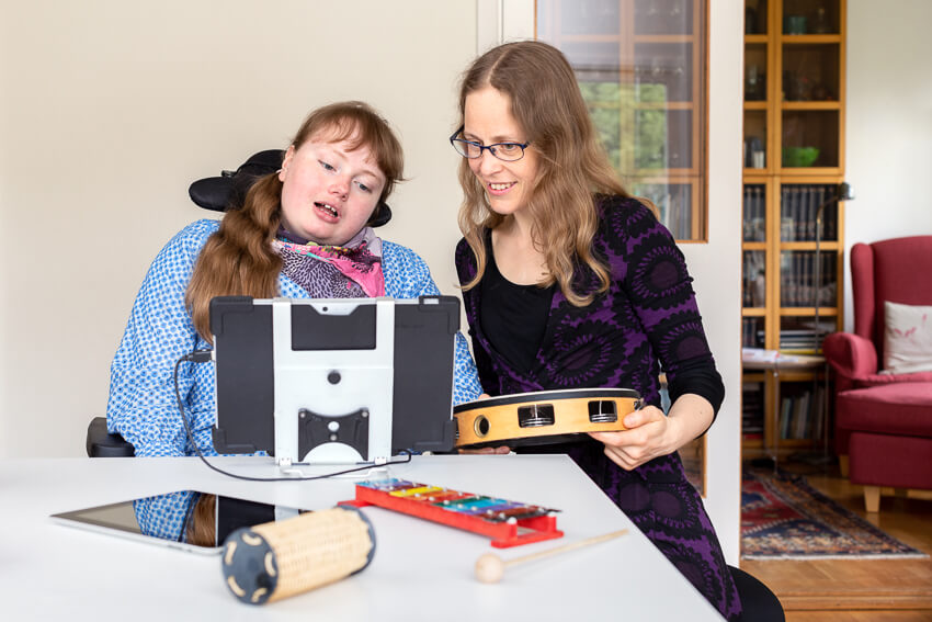 Två kvinnor tittar på en datorskärm, det ligger även rytminstrument på bordet 